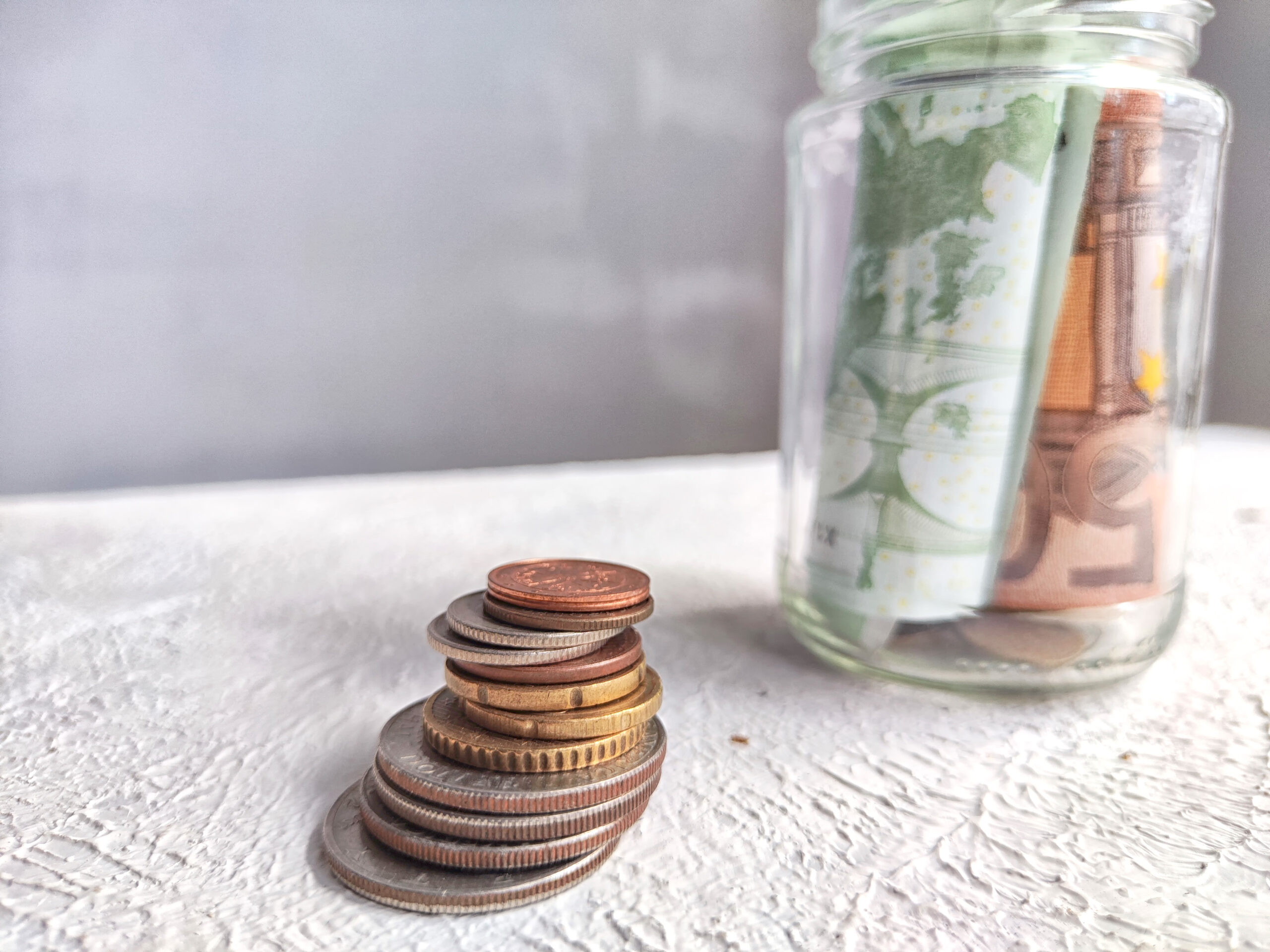 Glass Jar Filled With Euro Banknotes and Coins on Table. Concept of savings ranging from small money to large